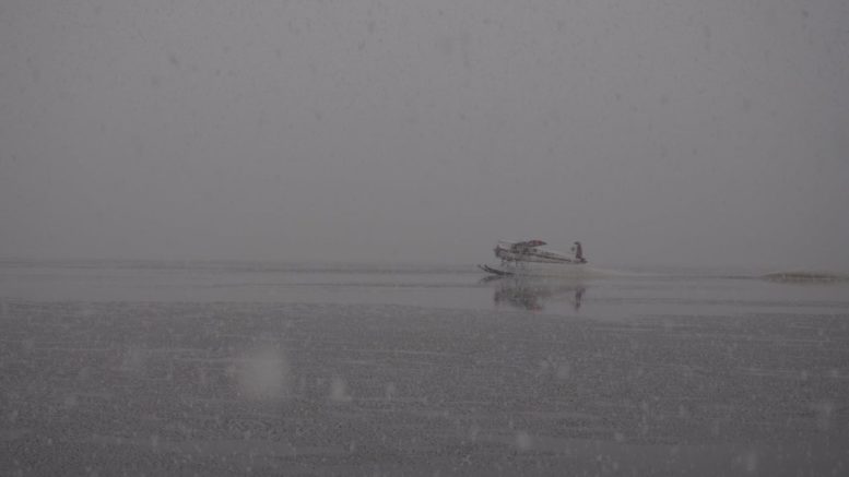 Image of a floatplane taxiing through the Thorne Bay during a snowstorm.