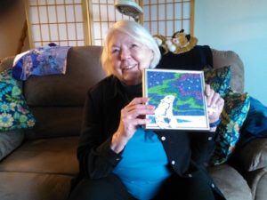 Joy Weber of Klawock, Alaska holding up her artwork