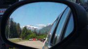 A photo taken through a truck side mirror of a snow-capped mountain near Klawock, Alaska.