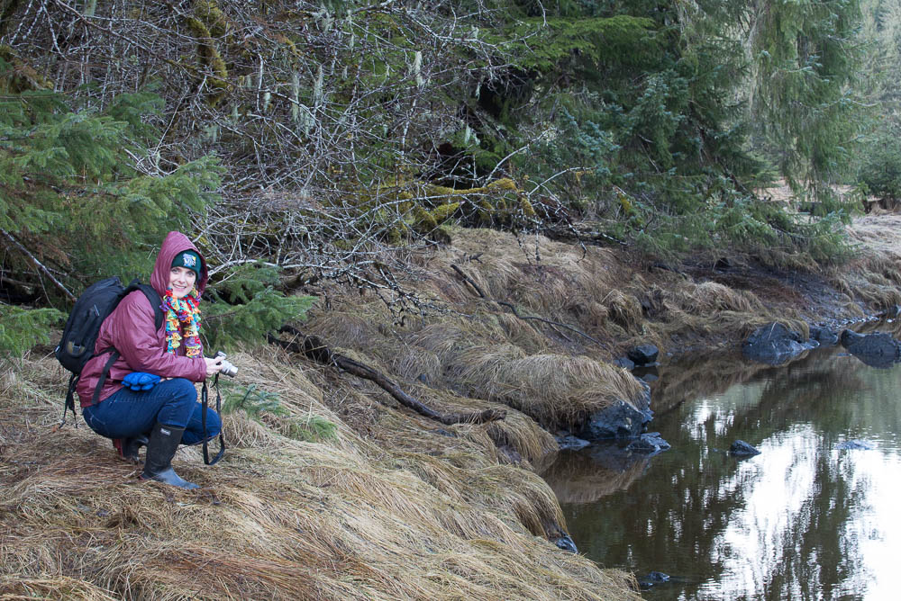 Melissa Cook stooping by a creek in southeast Alaska