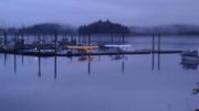 Two floatplanes parked in dock slips in Thorne Bay in a heavily cloudy dark day.