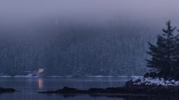 South side of Thorne Bay, Alaska foggy bay with little cabin in the distance surround by a mountain of trees