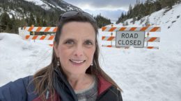 Melissa Cook standing by a snow bank with a road closed sign