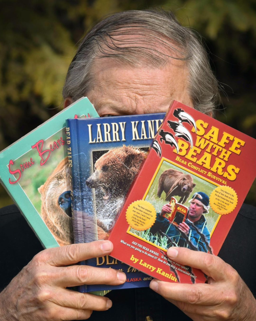 Larry Kaniut holds up a few of his books covering his face